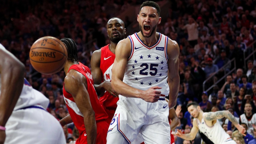 Ben Simmons screams and clenches his fist while wearing a white singlet with stars on it