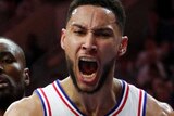 Ben Simmons screams and clenches his fist while wearing a white singlet with stars on it
