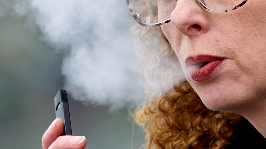 Close up of woman exhaling while vaping.