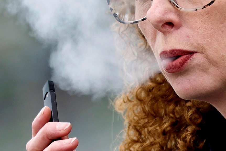 Close up of woman exhaling while vaping.