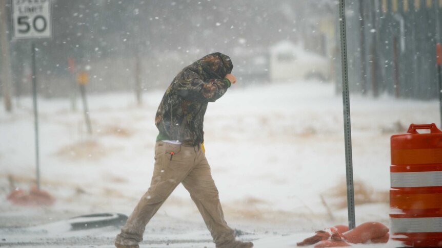 A Texas highway worker tries to shield himself from snow while walking to his truck