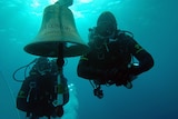 Italian Carabinieri divers pass by the bell of the stricken Costa Concordia luxury liner