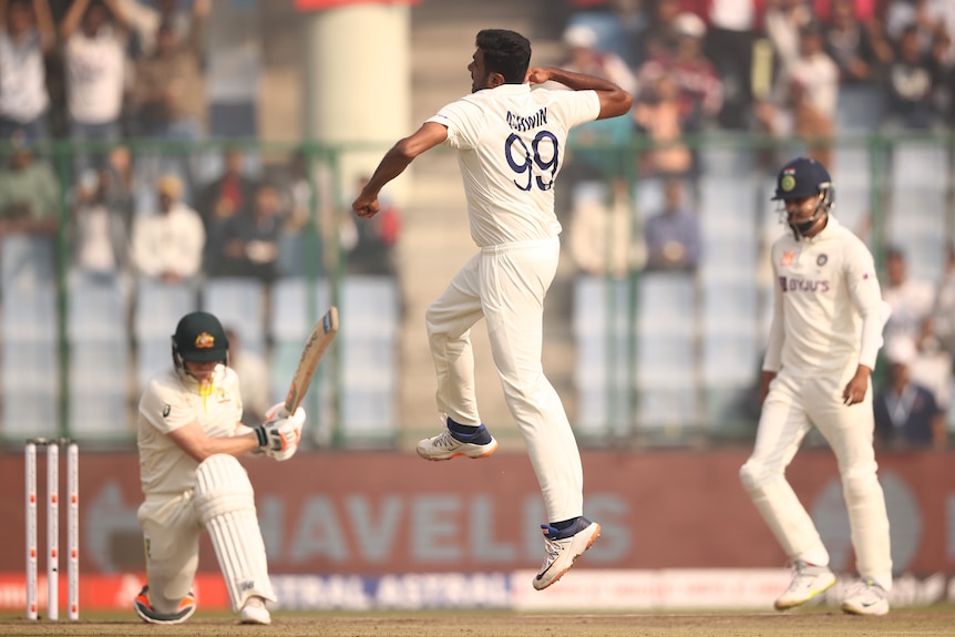 Ravichandran Ashwin leaps in the air as Steve Smith is shown on his knees