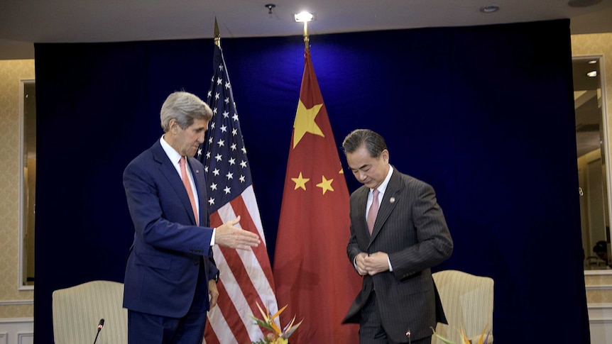 John Kerry (L) reaches to shake China's foreign minister Wang Yi's hand before the talks.
