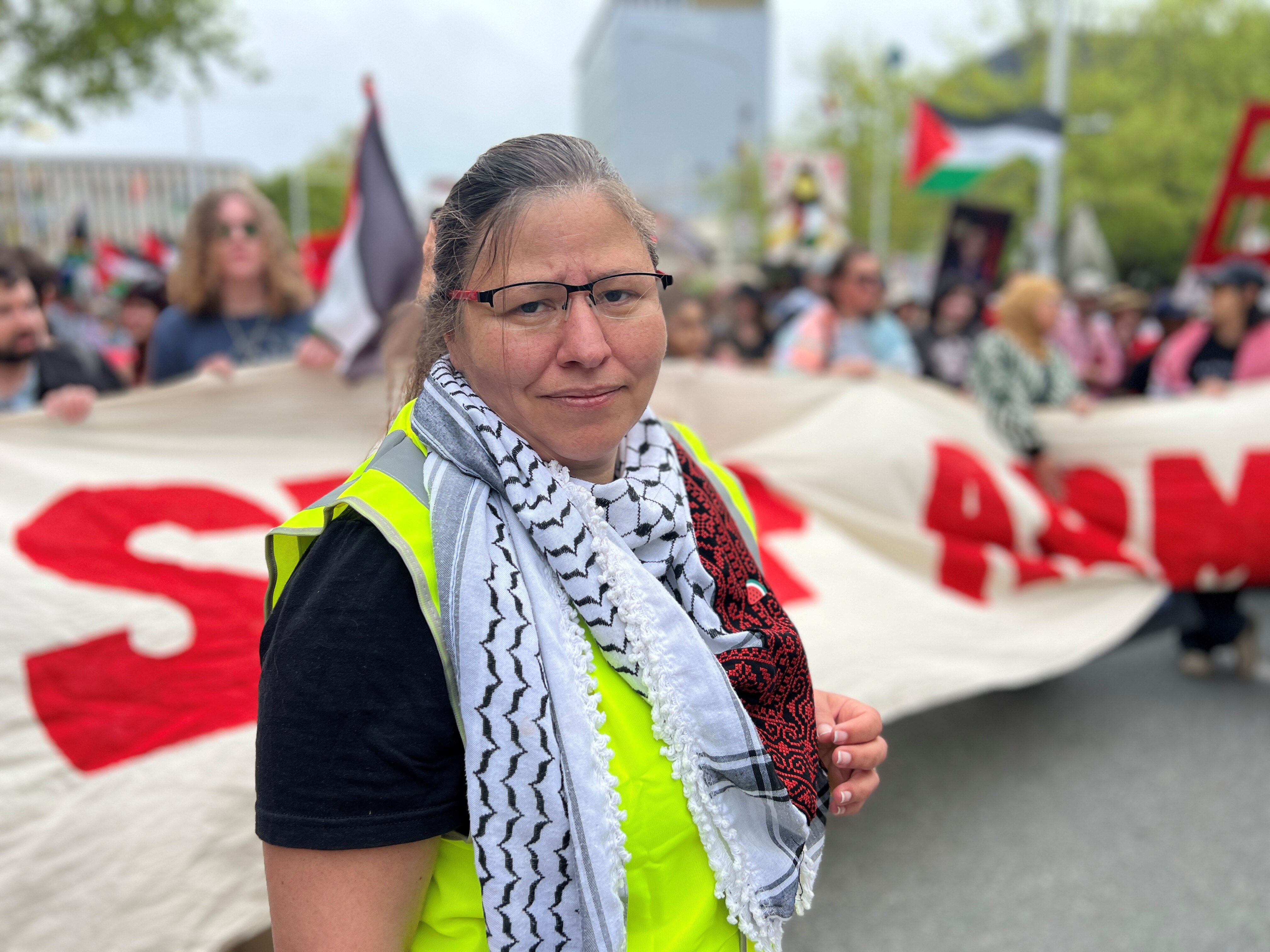 A woman wearing a hi-vis vest taking part in a march. 