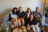 Young man with oxygen sitting on a couch surrounded by his mum, dad, sister and girlfriends 