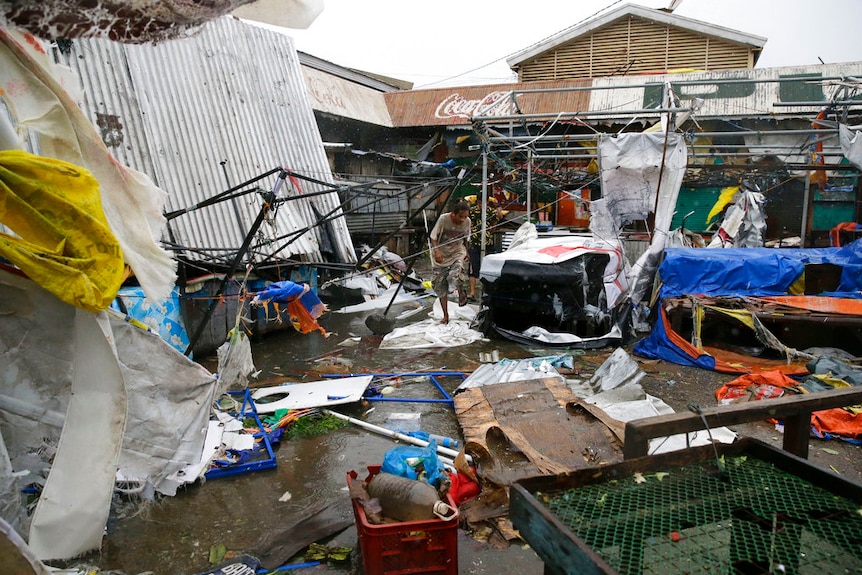 Residents walk along destroyed stalls at a public market due to strong winds.