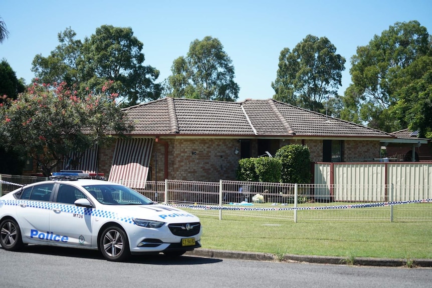 A police car and police tape in front of a house.