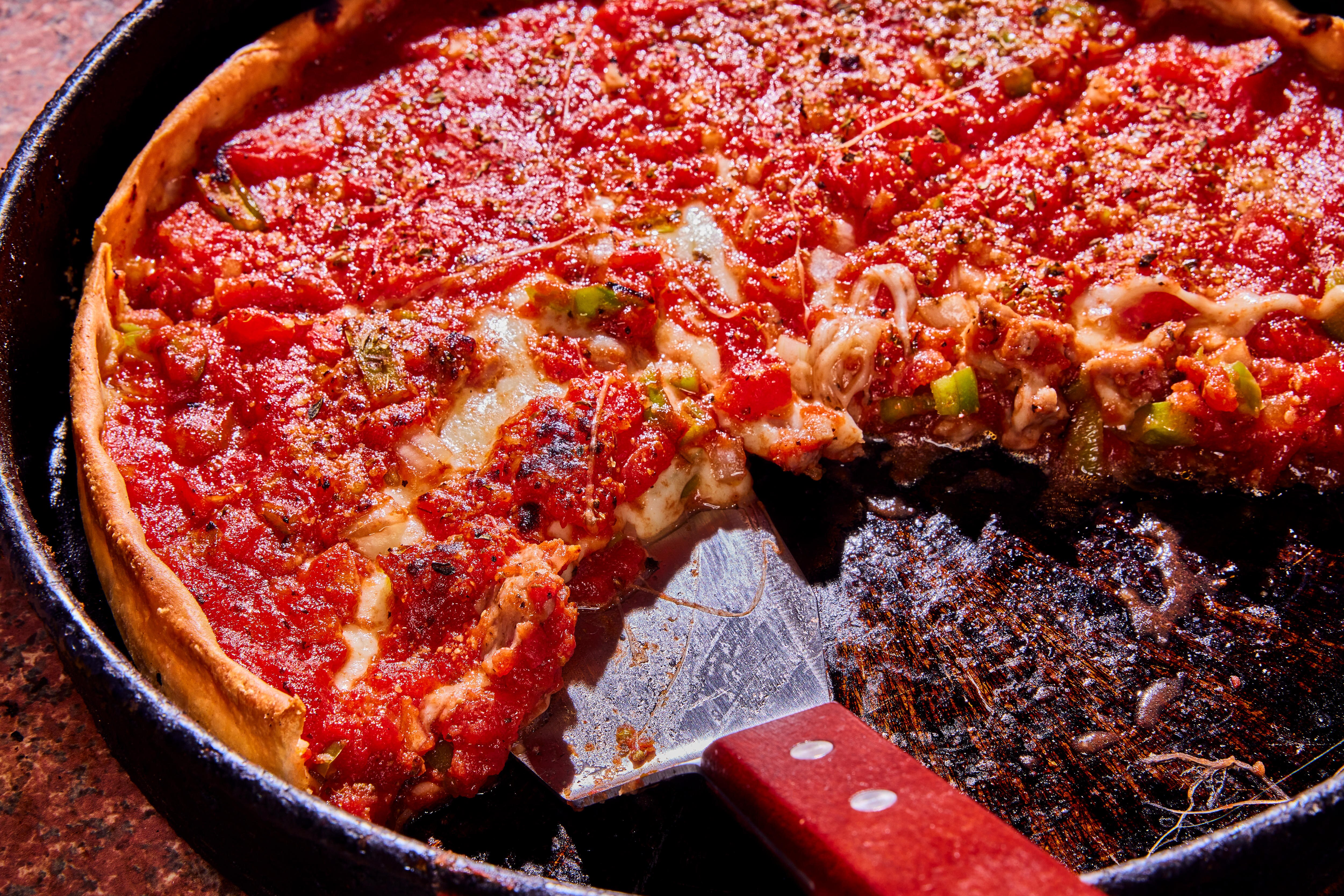 A deep dish pizza with plenty of cheese and sauce and green capsicum