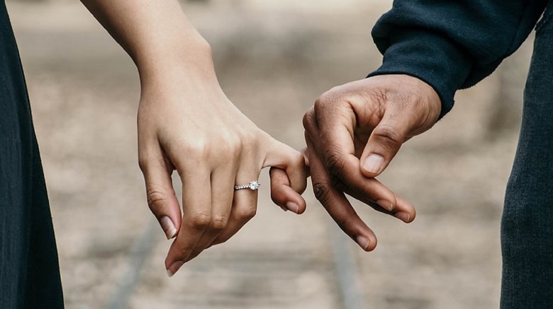 Couple linking pinkie fingers for a story on joint bank accounts