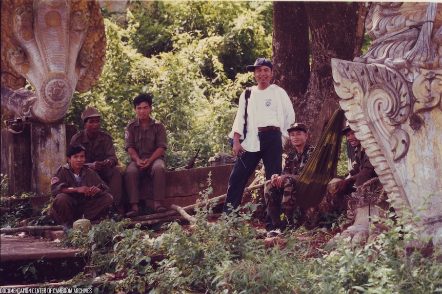 这张照片摄于1999年。照片上，昌裕身穿白衣，正在进行野外作业。他毕生都致力于记录红色高棉时期实行种族灭绝的情况。