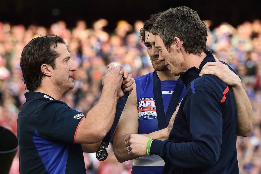 Western Bulldogs coach Luke Beveridge (L) gives injured Robert Murphy (R) his grand final medal.