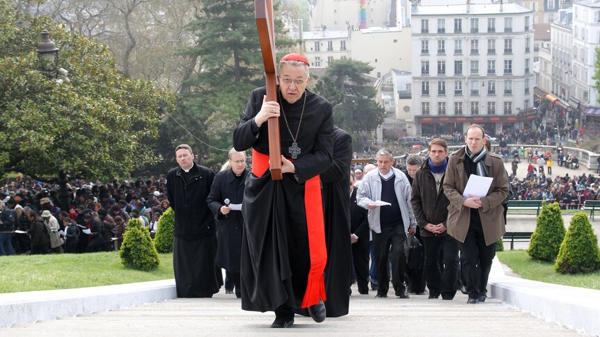 French bishop Andre Vingt-Trois carries a wooden cross during a Good Friday procession to commemorate the death of Christ