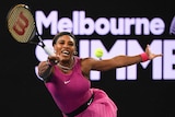 A tennis player grimaces as she reaches to hit a forehand return during a match.