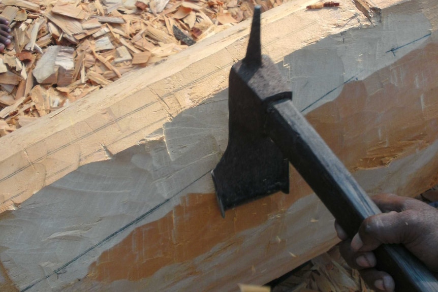 A more modern, steel adze being used to shape the outside of a canoe hull.