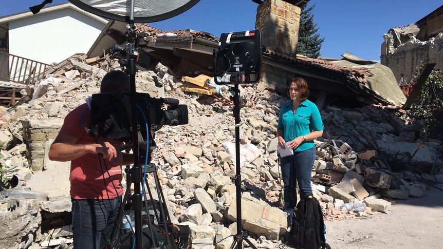 Millar and cameraman standing in rubble of a destroyed house.