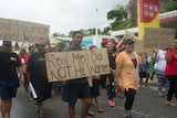 A man holds a banner that reads "real men do not hit women"