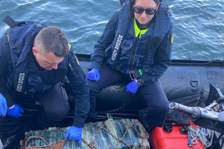 Borer police officers sitting on a boat with the package of cocaine seized