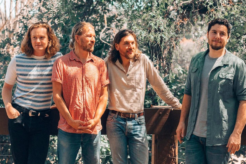 The four members of the band with trees in the background