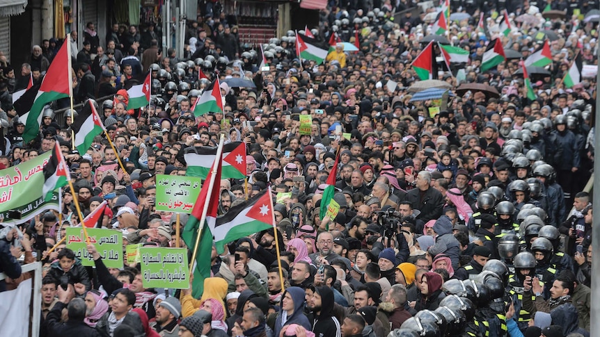 Protesters carry Jordanian and Palestinian flags and slogans during a protest against Trump's Middle East peace plan.