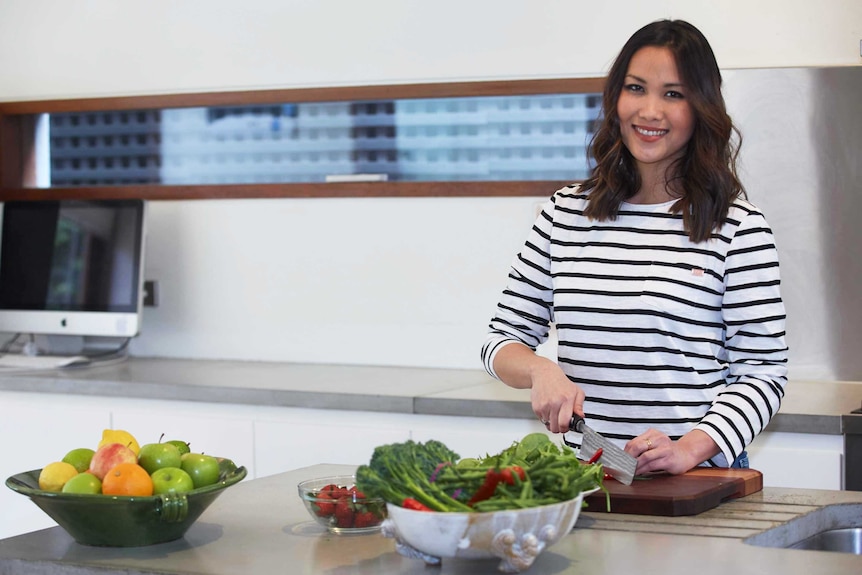 Diana Chan in a kitchen cutting chilli and preparing other vegetables.