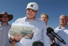 Prime Minister Scott Morrison holds up a photo of what a property used to look like before the drought.