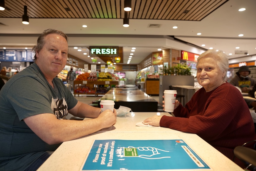 Man sitting with his elderly mother in a food court.