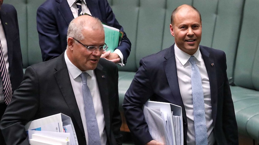 Scott Morrison and Josh Frydenberg, both holding stacks of folders, smile as they walk through the House of Reps.