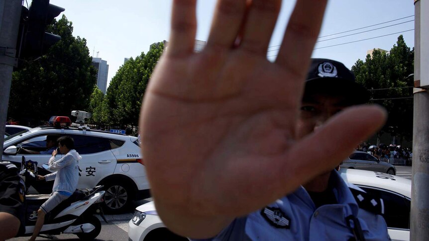 A police officer holds up a hand towards a camera