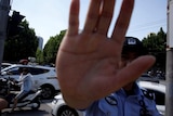 A police officer holds up a hand towards a camera