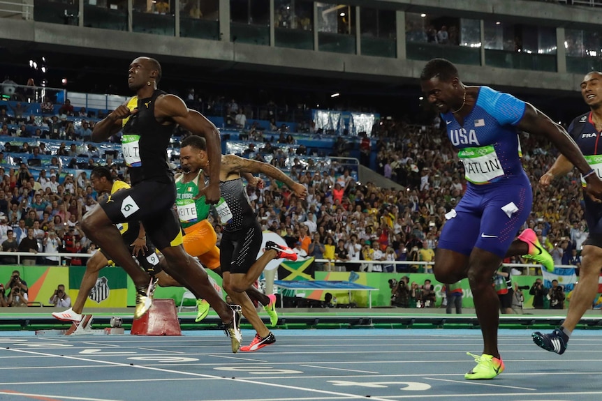 Jamaica's Usain Bolt (L) crosses the line to win the men's 100 metre final at the Rio Olympics.