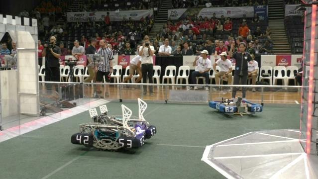 Robotic vehicles on a race track with an audience behind
