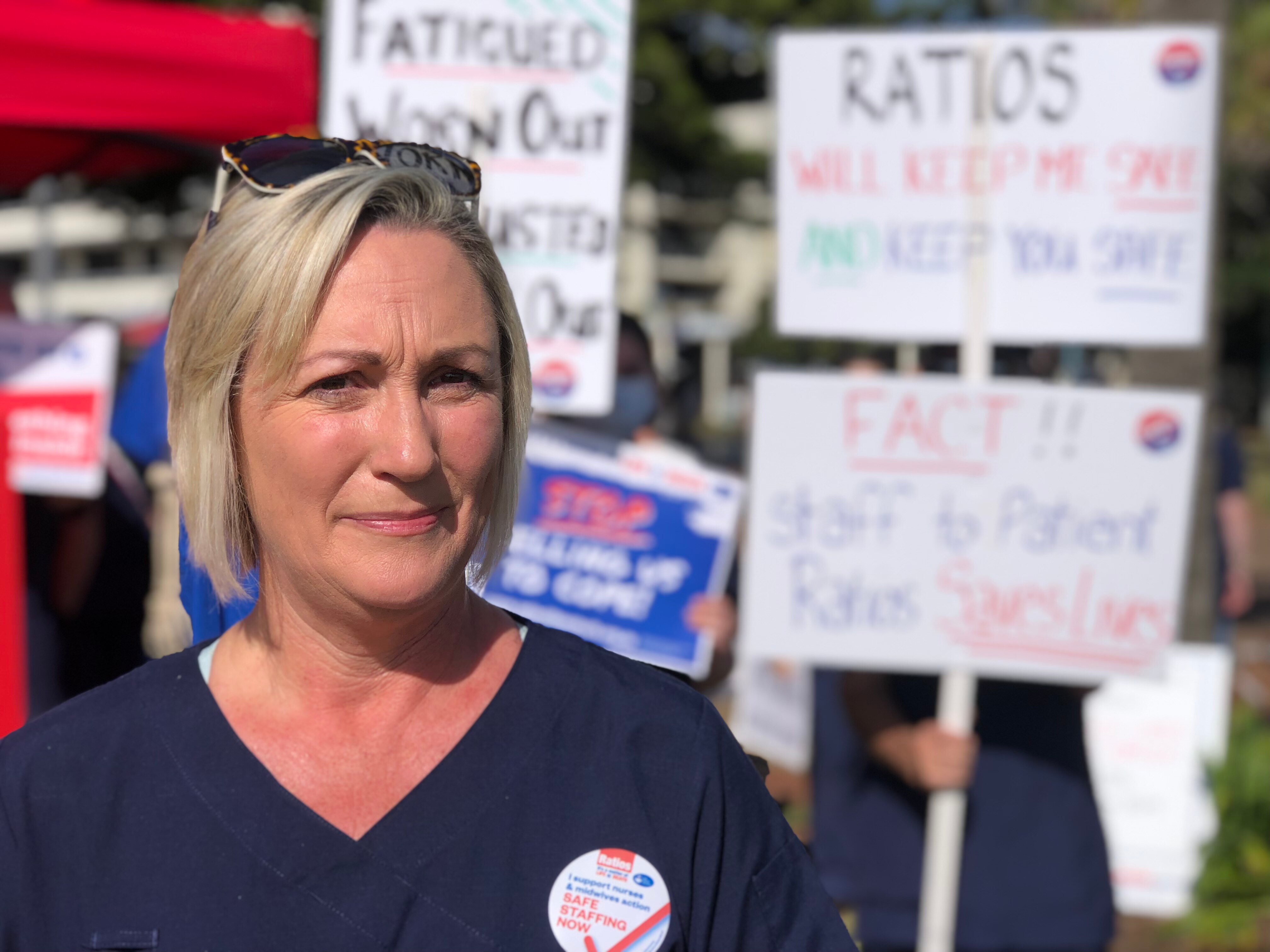 A woman stands in front of striking nurses