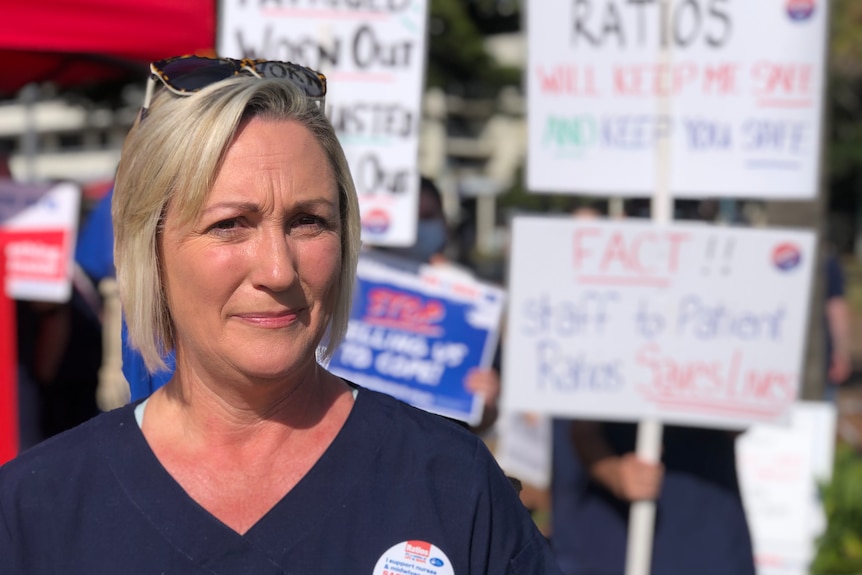 A woman stands in front of striking nurses