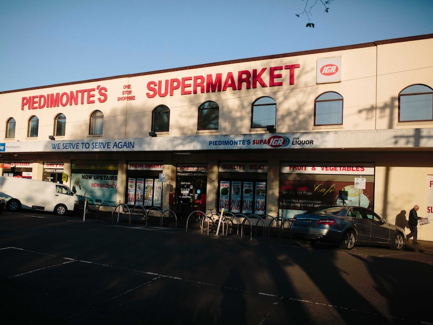 Piedimonte's Supermarket at sunrise as a man walks long reading his paper