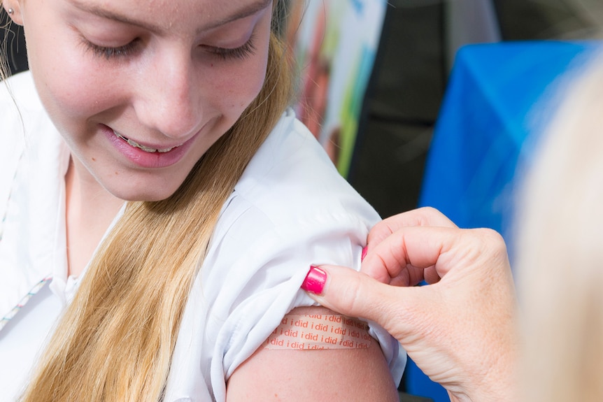 A nurse applies a bandaid to a student.