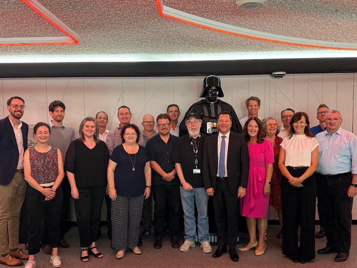 Grupo de personas sonriendo frente a Darthvader