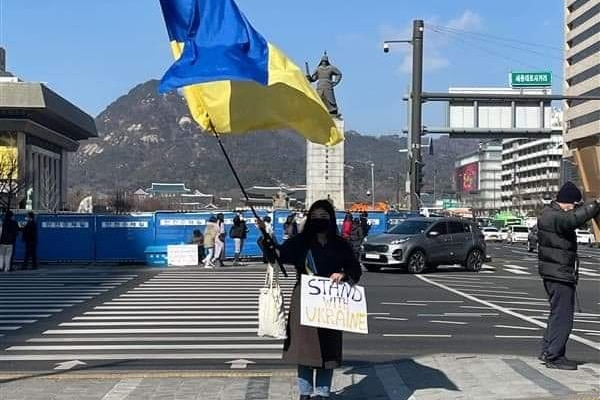 拿着乌克兰国旗和横幅的妇女 "与乌克兰站在一起".