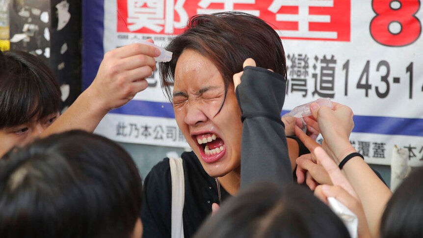 A woman reacts after being pepper sprayed by police in Hong Kong Monday