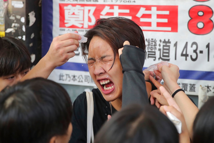 A woman reacts after being pepper sprayed by police in Hong Kong Monday