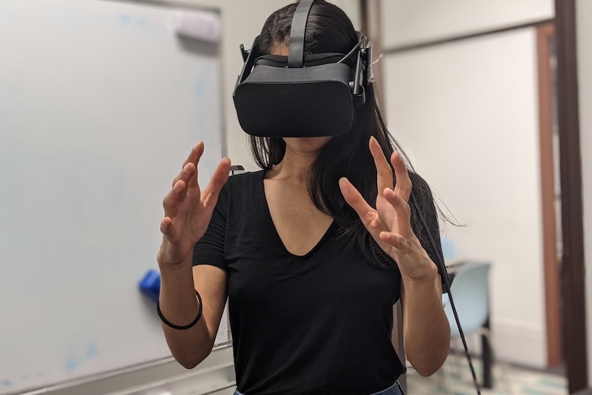 All in the Mind presenter Sana Qadar wearing a VR headset and holding her hands in front of her