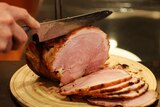 Person cutting a glazed ham
