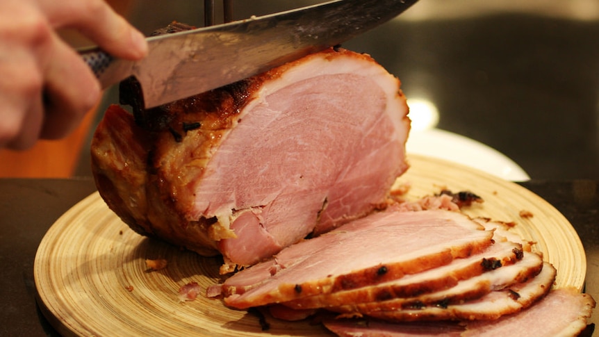 Person cutting a glazed ham