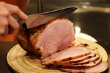 Person cutting a glazed ham