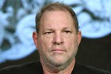 A close-up photograph of Harvey Weinstein speaking at a panel in 2016.