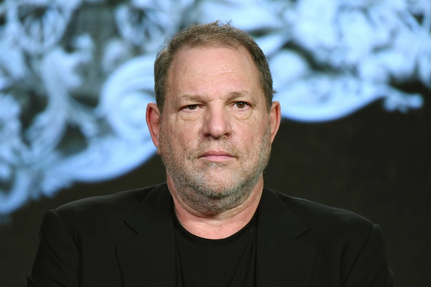 A close-up photograph of Harvey Weinstein speaking at a panel in 2016.