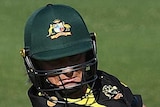An Australian female T20 cricketer wearing a helmet plays a cut shot to her right against New Zealand in Brisbane.