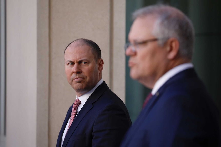 Morrison is out of focus in the foreground, Frydenberg in focus looking towards PM.
