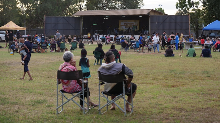 a crowd on a lawn watches bands on a stage