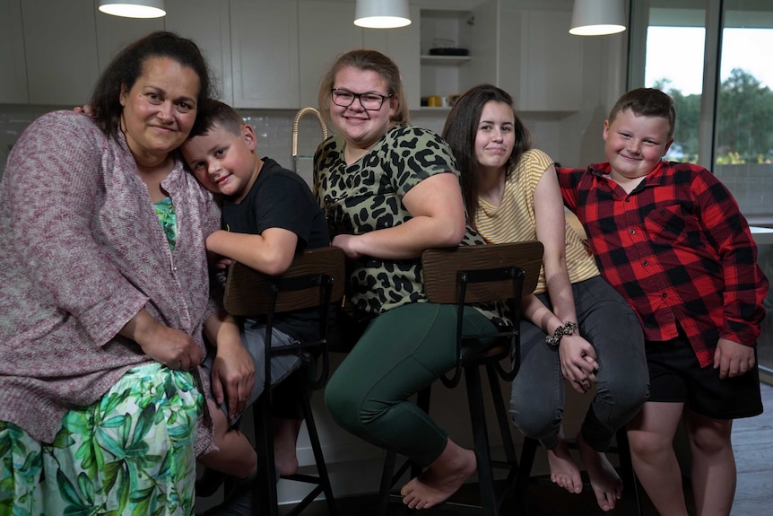 A family shot shows the four kids hugging mum.